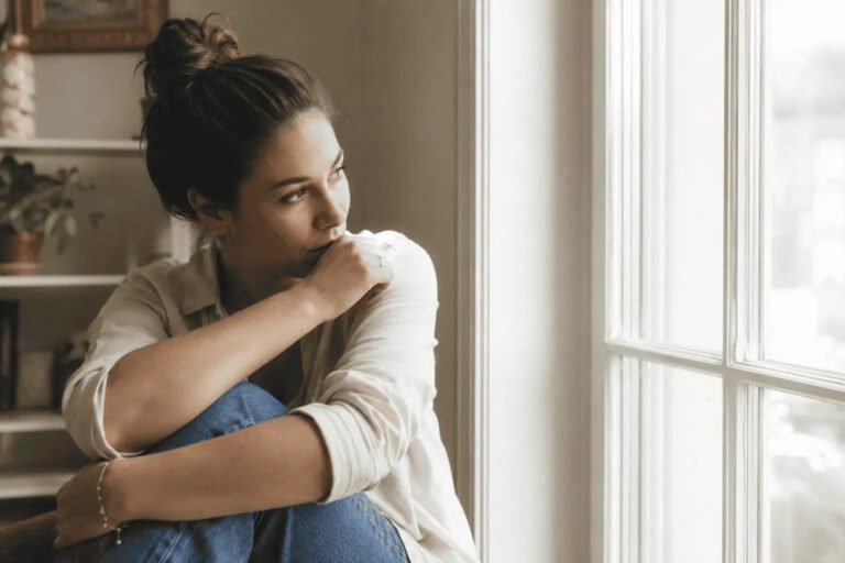 femme HPI pensive près dune fenêtre, haut potentiel intellectuel au féminin